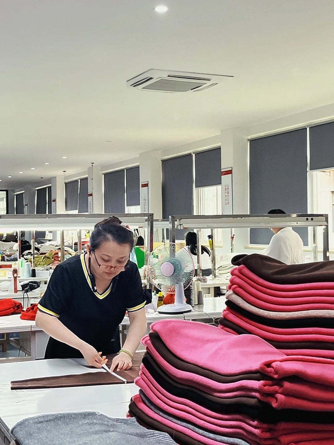 QC workshop real shot, worker measures multi-color anti-pilling premium knit sweaters, strict finished garment dimension & appearance inspection factory photo