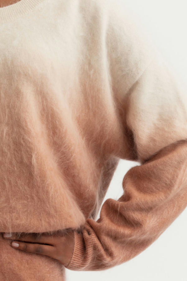 Close-up texture shot of gradient dip-dye brushed cashmere crew neck sweater, peach to off-white ombre fuzzy halo cashmere knit fabric detail, soft brushed fleece women pullover texture photo