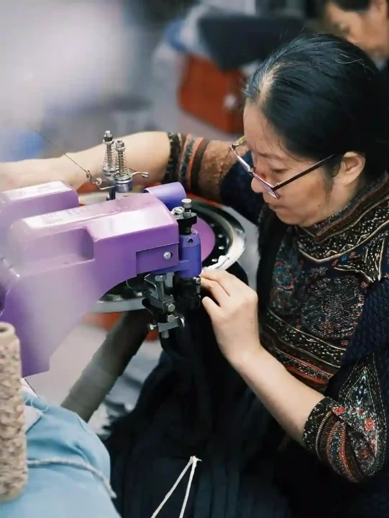 Seamstress operating linking machine in knitwear factory, custom knitwear for influencers and creator brands