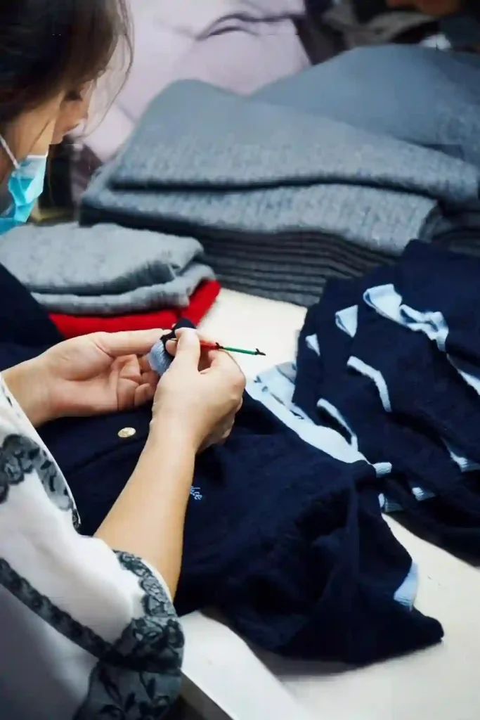 QC inspector checking finished knitwear garments, knitwear quality control in factory