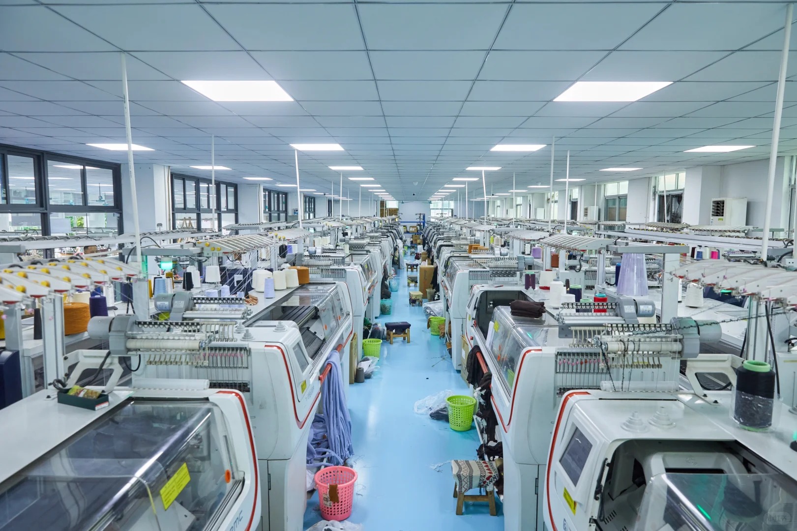 Wide panoramic factory workshop shot of full-auto computerized flat knitting machines, clean knitwear OEM production workshop, bulk private label cashmere sweater manufacturing factory interior