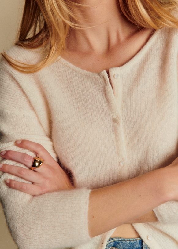 Close-up lifestyle shot of cream ultra-fine 50% kid mohair round neck button cardigan, soft wispy halo fuzzy knit texture, lightweight luxury women layering knit outerwear