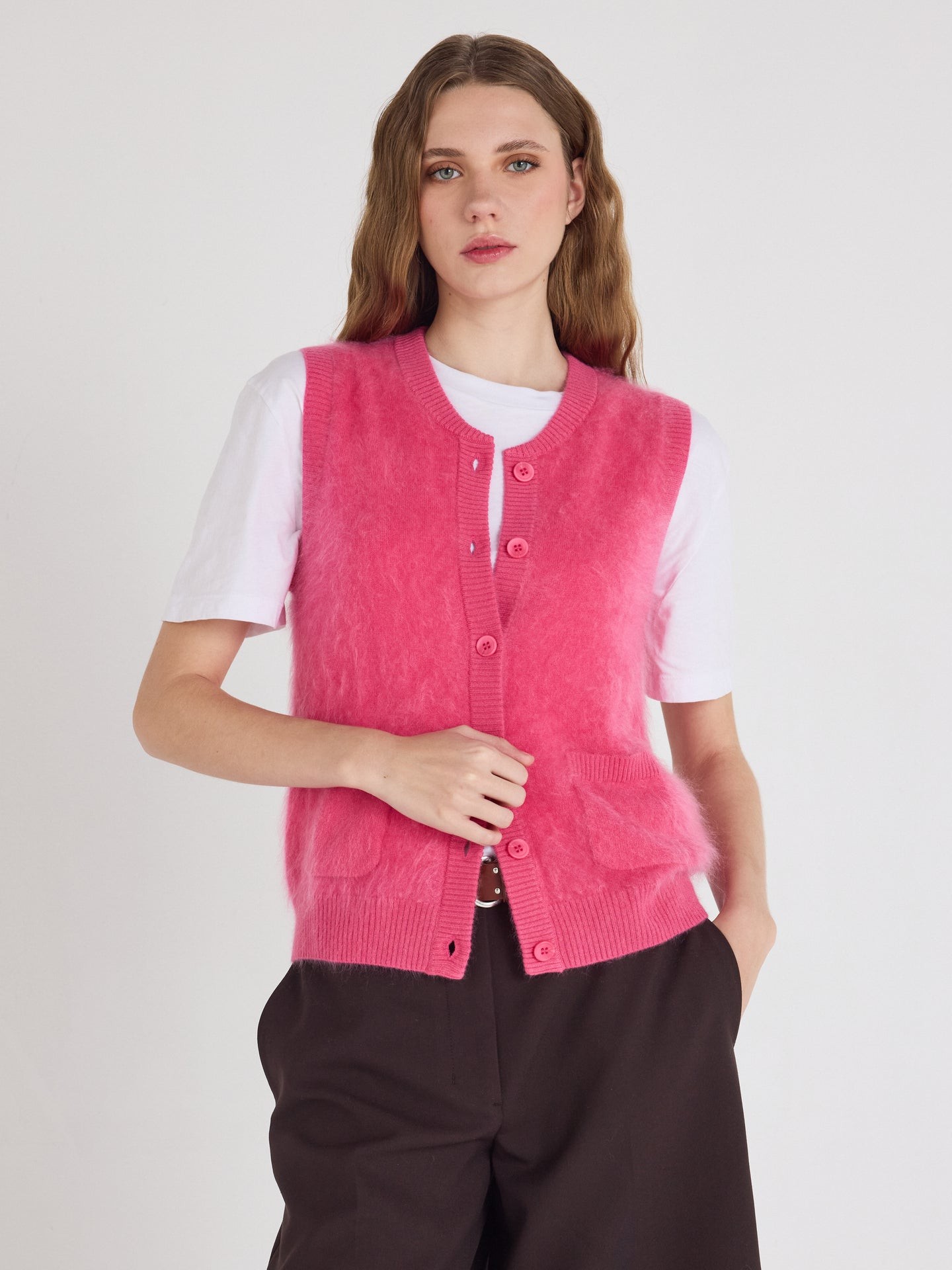 Studio model shot of pop pink fluffy cashmere fleece sleeveless vest cardigan, V-neck button front knit waistcoat with side pockets, fuzzy halo cashmere casual layering outerwear